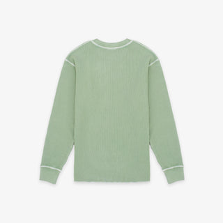 A sage green ribbed knit long-sleeve shirt with white contrast stitching on the shoulders, cuffs, and collar, shown flat against a light gray background.