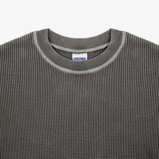 Close-up of a dark gray waffle-knit crewneck sweater with a ribbed collar and a visible Dri-Wax label inside the neckline.