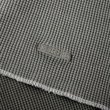 Close-up of a gray textured fabric with a visible woven brand patch reading 'BELLEWE' and a folded edge showing the material texture.
