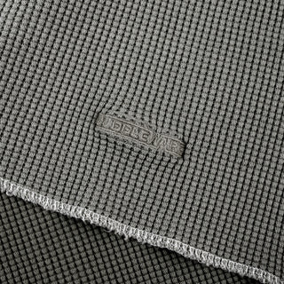 Close-up of a gray textured fabric with a visible woven brand patch reading 'BELLEWE' and a folded edge showing the material texture.