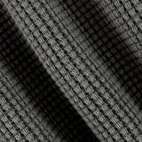 Close-up of a black and gray textured knit fabric with a diagonal shadow creating contrast.