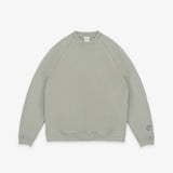 A light sage green crewneck sweatshirt with raglan sleeves, laid flat against a clean white background.
