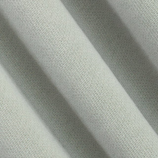 A close-up of draped light sage green knit fabric showing its fine woven texture and soft folds.