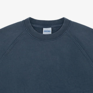 Close-up of a crewneck sweatshirt in a dark slate blue-gray color, showing the inner neck label which reads 'SWEATSHIRTS'.