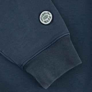 Close-up of a dark slate blue sweatshirt sleeve featuring a circular embroidered 'Dubble Wars' patch on the cuff.
