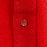 Close-up of a bright red button-down shirt fabric with a matching red button on the placket.