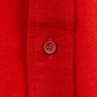 Close-up of a bright red button-down shirt fabric with a matching red button on the placket.