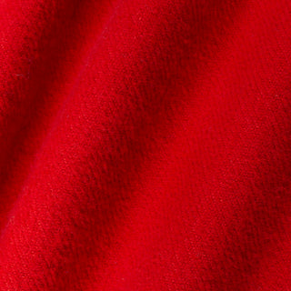 A close-up of bright red textured fabric with soft diagonal folds and a plush, nubby surface.