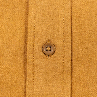 Close-up of a mustard yellow knit fabric garment with a single brown button on the front placket.