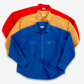 Three long-sleeve button-up shirts in red, tan, and royal blue, arranged in a stacked fan layout on a light gray background.