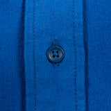 Close-up of a vibrant royal blue textured fabric with vertical stitched channels and a matching dark blue button.