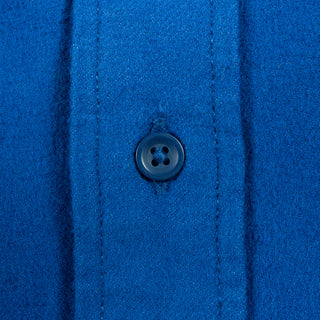 Close-up of a vibrant royal blue textured fabric with vertical stitched channels and a matching dark blue button.