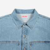 Close-up of a light blue denim button-up shirt collar and chest area, showing the Doubleware brand label inside the neck and a small Doubleware tag on the chest pocket.