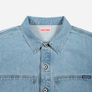 Close-up of a light blue denim button-up shirt collar and chest area, showing the Doubleware brand label inside the neck and a small Doubleware tag on the chest pocket.