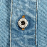Close-up of a light blue denim garment with orange contrast stitching and a silver metal button embossed with the brand name 'CUBBLEWARE'.