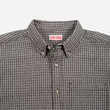 Close-up of a button-down shirt collar with a small red and white Bubbleware neck label, featuring a fine brown and beige checkered pattern.