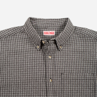 Close-up of a button-down shirt collar with a small red and white Bubbleware neck label, featuring a fine brown and beige checkered pattern.