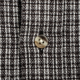 Close-up of a black and white woven fabric with a repeating geometric pattern and a single round metallic button near the center.