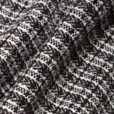 Close-up of a textured knit fabric with a black and off-white woven pattern, showing the detailed weave and soft folds.