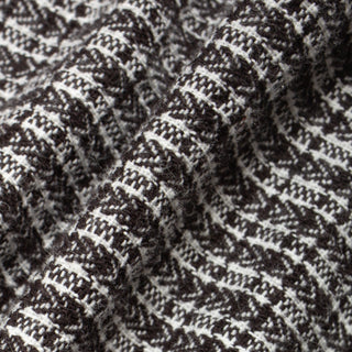 Close-up of a textured knit fabric with a black and off-white woven pattern, showing the detailed weave and soft folds.