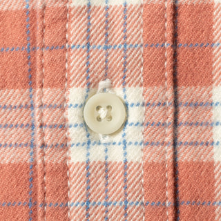 Close-up of a plaid fabric with a white button, showing a pattern of coral pink, white, and light blue stripes.
