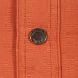 Close-up of an orange woven fabric with vertical stitched channels and a round dark metal button embossed with the brand name 'DUBBLE WARE'.