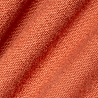 A close-up of textured fabric in a warm rust or terracotta color, shown with soft folds and a woven surface.