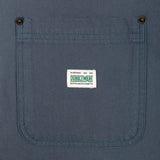 Close-up of a blue canvas work shirt pocket with two metal snap buttons and a white Dubbleware brand label stitched in the center.